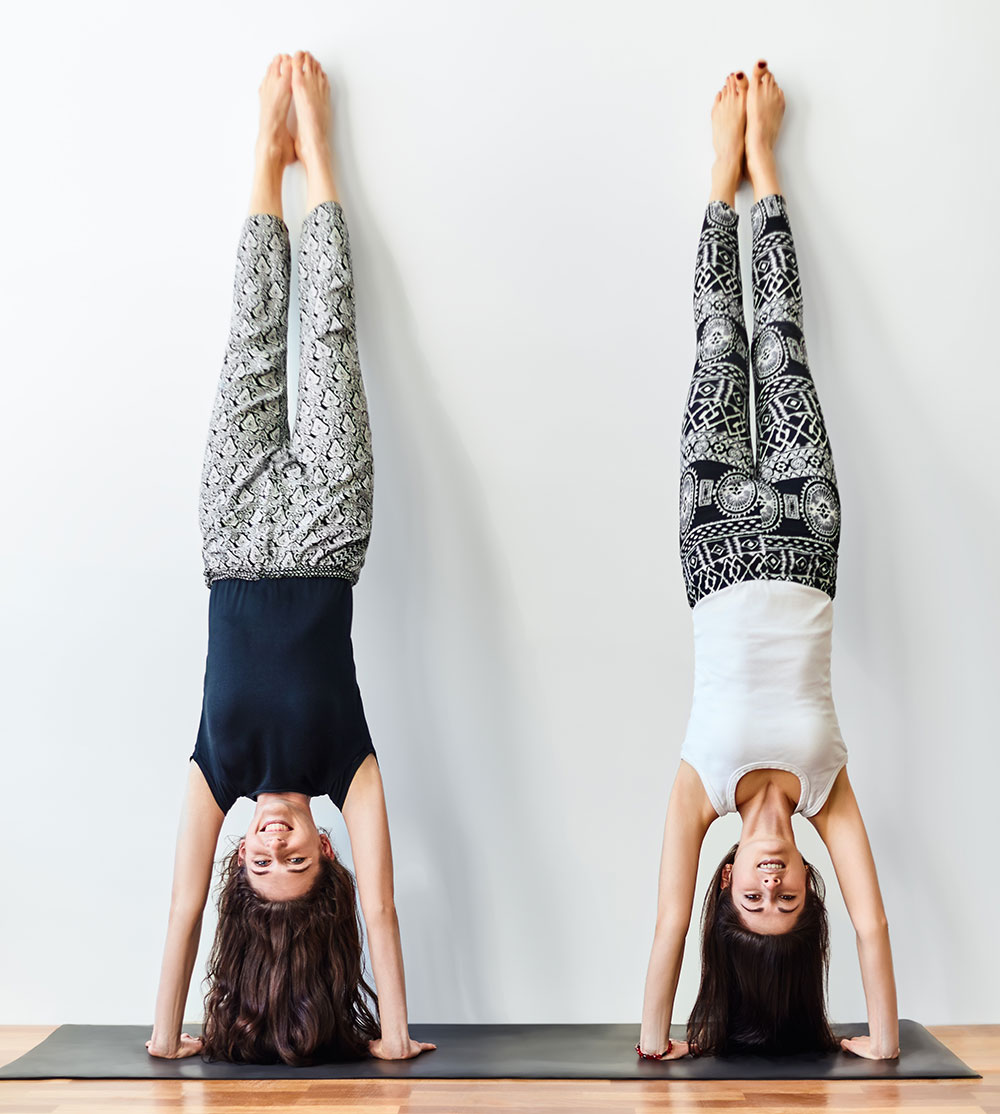 Two young women doing yoga handstand pose. Adho Mukha Vrksasana